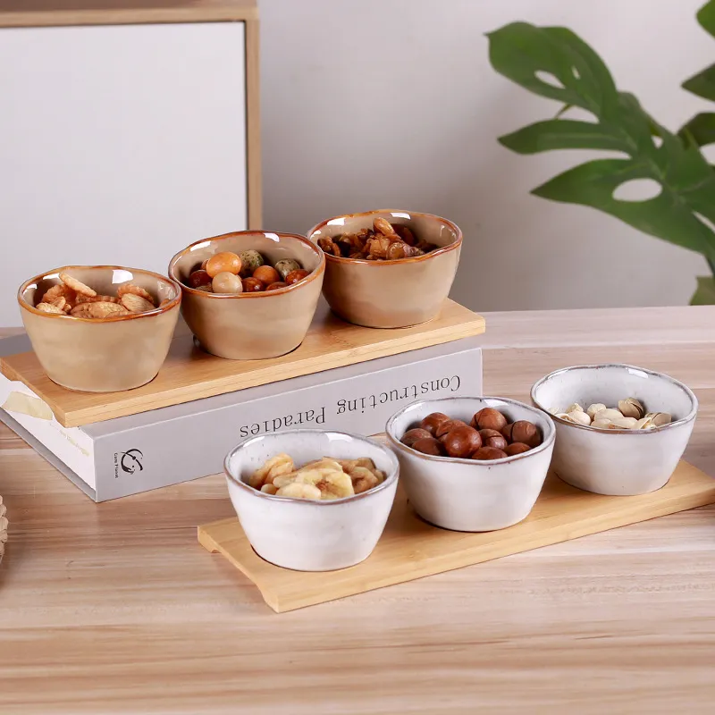 Pr&aacute;ctico juego de platos y cuencos de cer&aacute;mica para aperitivos con bandeja de bamb&uacute; para frutas secas y caramelos. 